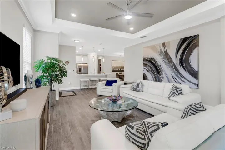Living area featuring a ceiling fan, recessed lighting, a tray ceiling, light wood-style flooring, and ornamental molding