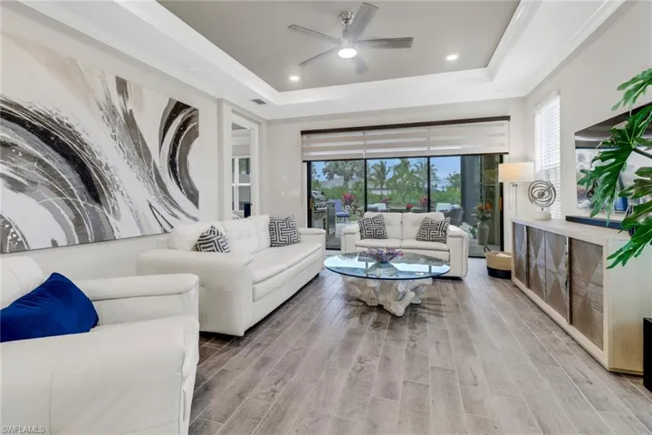 Living room with wood tiled floors, ceiling fan, ornamental molding, a tray ceiling, and recessed lighting