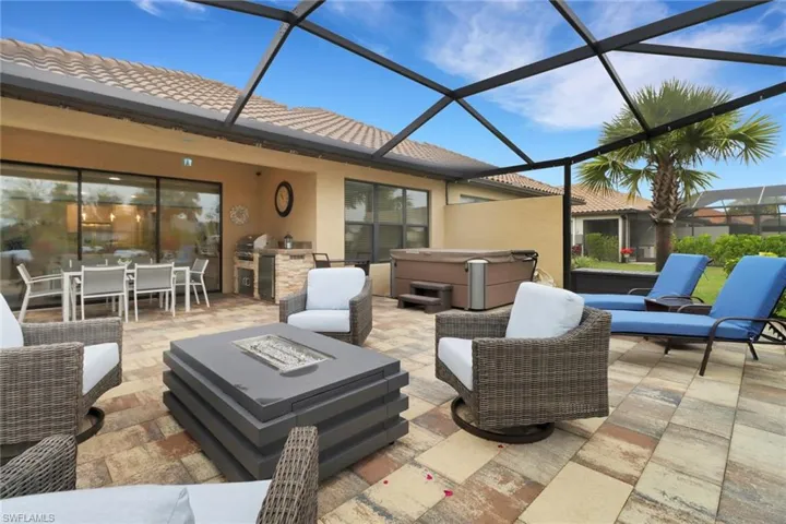 View of patio with outdoor lounge area, a sunroom, glass enclosure, area for grilling, and a hot tub