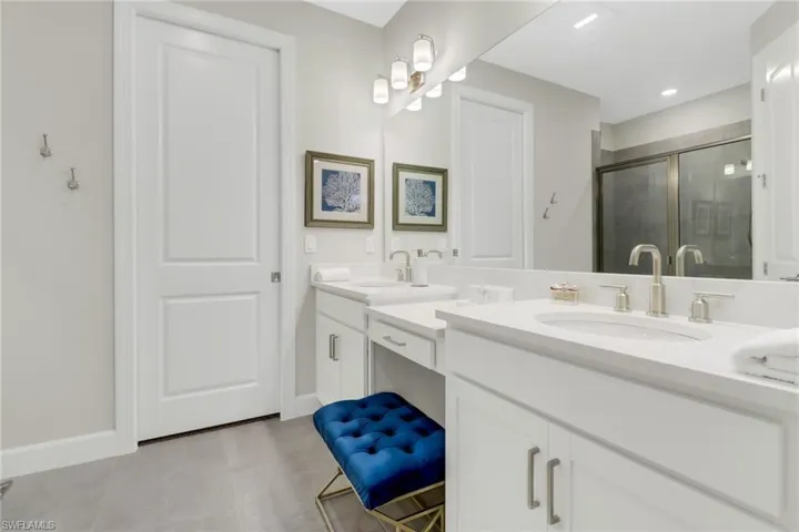 Bathroom featuring double vanity, a stall shower, and light tile patterned floors