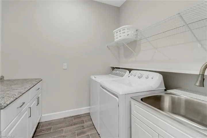 Laundry area featuring wood tiled floors, washer and clothes dryer, and cabinet space