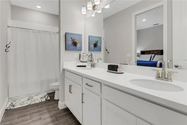 Full bathroom with double vanity, wood finish floors, ensuite bath, recessed lighting, and shower / tub combo with curtain