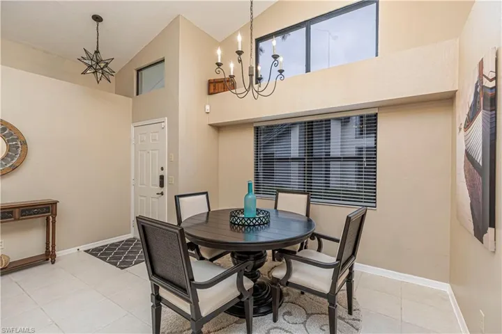 Dining area featuring high vaulted ceiling, a notable chandelier, and light tile patterned flooring