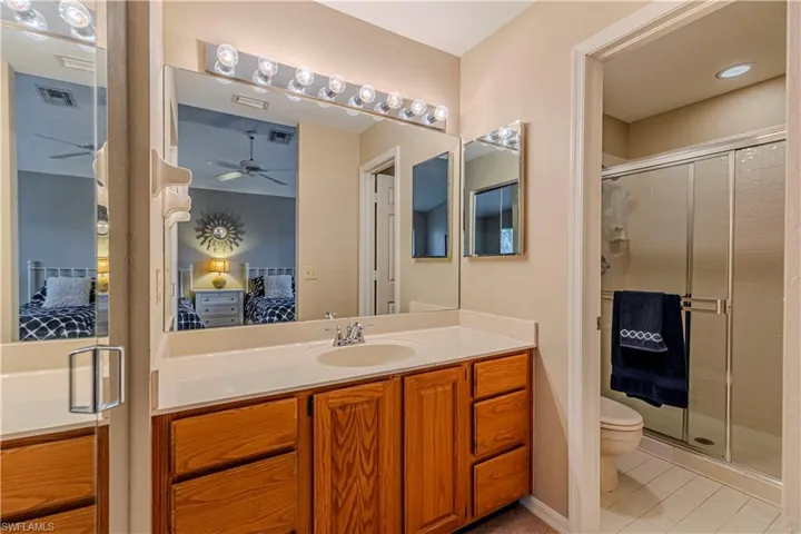Second bathroom featuring tile patterned flooring, vanity, toilet, and a shower with shower door