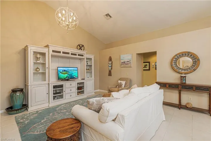 Tiled living room with lofted ceiling and a chandelier