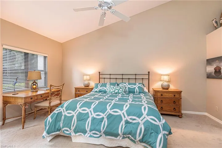 Carpeted bedroom featuring ceiling fan and lofted ceiling
