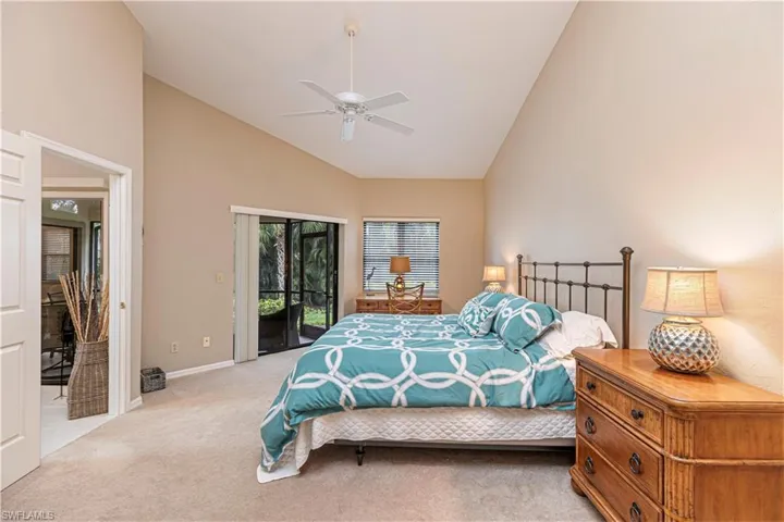 Bedroom with high vaulted ceiling, ceiling fan, light colored carpet, and access to outside