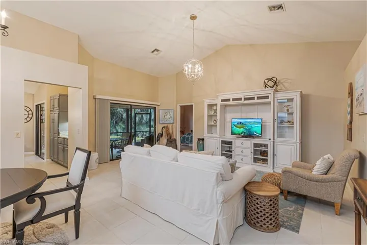Living room with light tile patterned flooring, high vaulted ceiling, and a chandelier