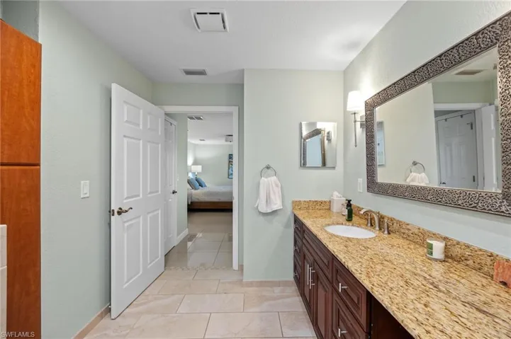 Full bath with ensuite bathroom, vanity, and light tile patterned floors
