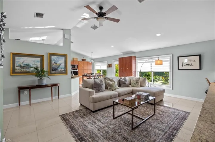 Living area featuring lofted ceiling, light tile patterned flooring, and a ceiling fan