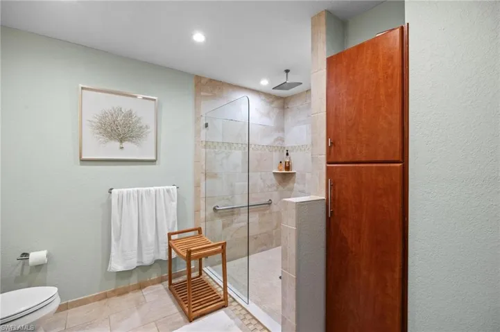 Bathroom with a textured wall, a walk in shower, and tile patterned floors