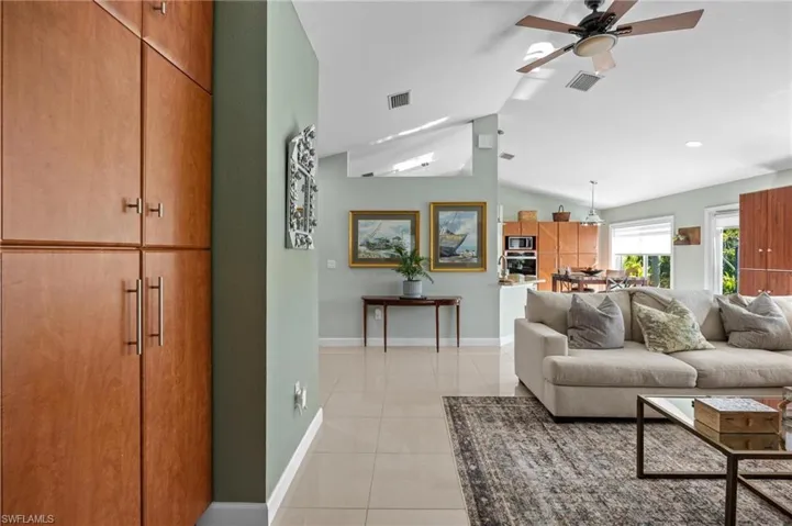 Living area with vaulted ceiling, light tile patterned floors, and ceiling fan