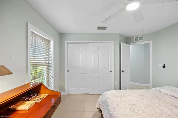 Bedroom with light tile patterned floors, a closet, and ceiling fan