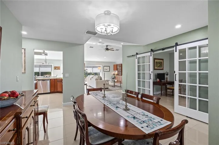 Dining room with a barn door, light tile patterned flooring, recessed lighting, and ceiling fan