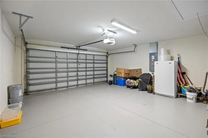 Garage with freestanding refrigerator, electric panel, and a garage door opener