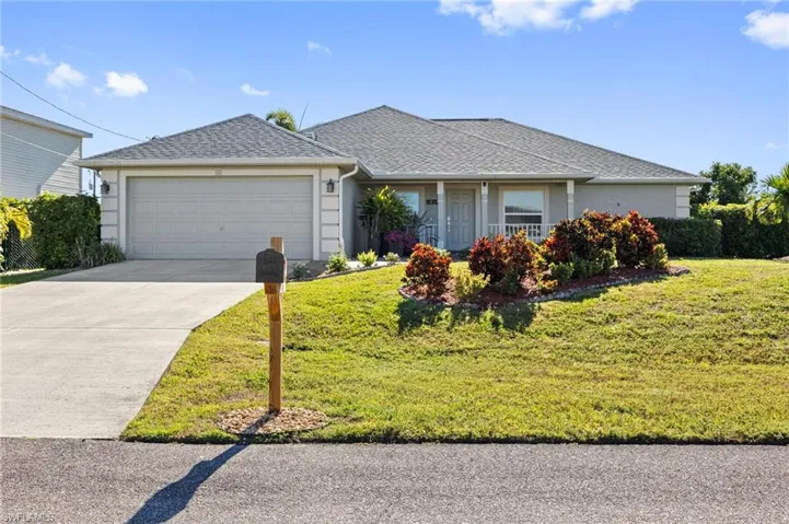 Ranch-style home with a shingled roof, a front yard, concrete driveway, and a garage