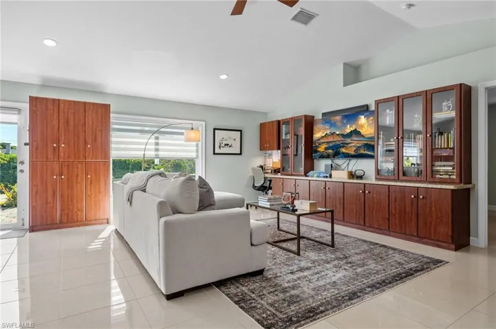 Living room with vaulted ceiling, light tile patterned flooring, ceiling fan, and recessed lighting