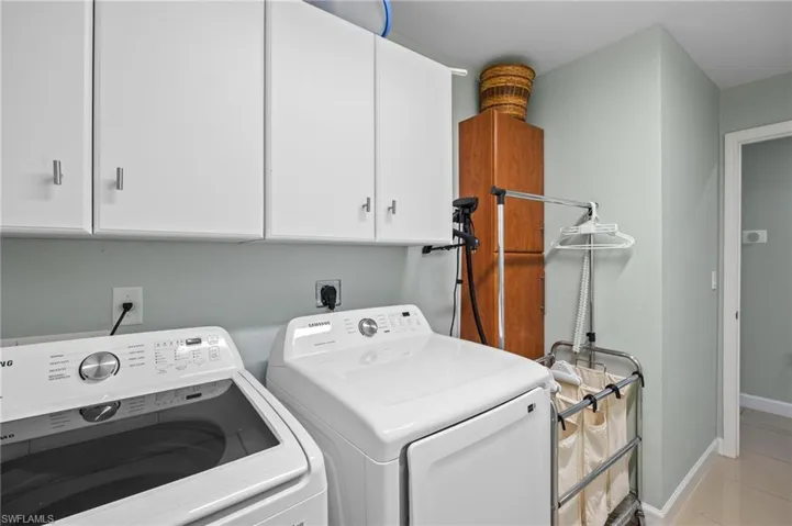 Washroom featuring independent washer and dryer, cabinet space, and light tile patterned floors