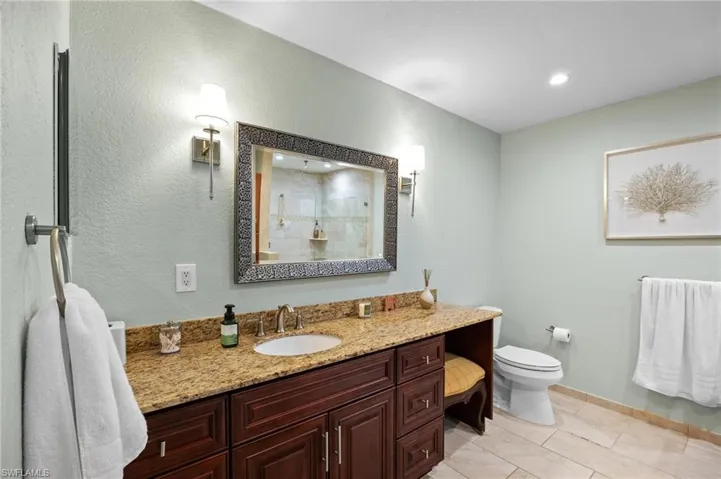 Full bath featuring vanity, a textured wall, tiled shower, light tile patterned floors, and recessed lighting