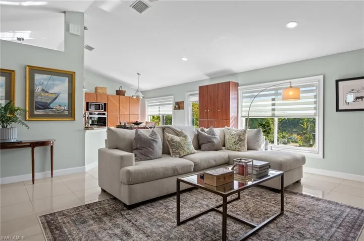 Living area with light tile patterned floors, vaulted ceiling, and recessed lighting