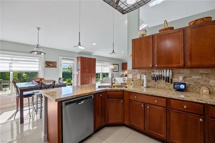 Kitchen featuring dishwasher, pendant lighting, light tile patterned floors, light stone counters, and recessed lighting