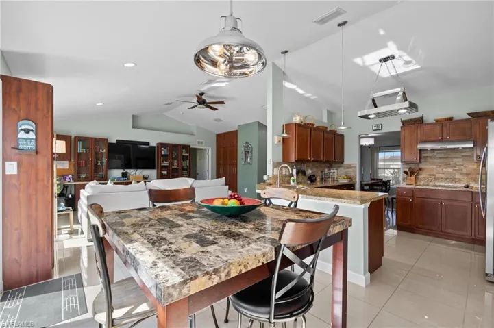 Dining room featuring vaulted ceiling, light tile patterned floors, and a ceiling fan