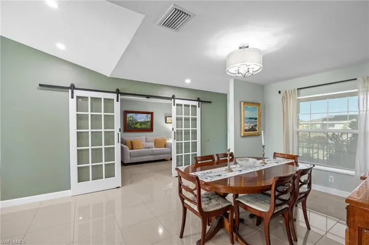 Dining space with a barn door, light tile patterned flooring, and recessed lighting