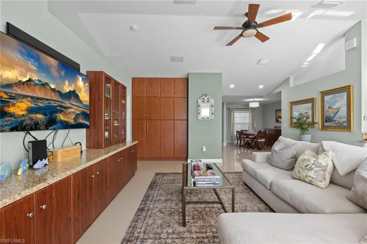 Living area featuring light tile patterned floors, lofted ceiling, ceiling fan, and recessed lighting