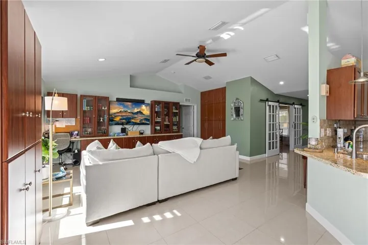 Living area with a barn door, ceiling fan, light tile patterned floors, lofted ceiling, and recessed lighting