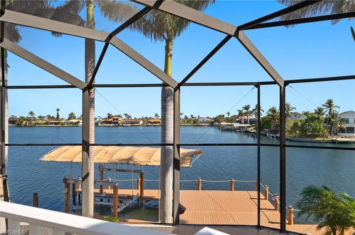 View of dock featuring glass enclosure, boat lift, and a water view