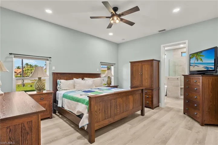 Bedroom featuring light wood finished floors, visible vents, recessed lighting, and connected bathroom