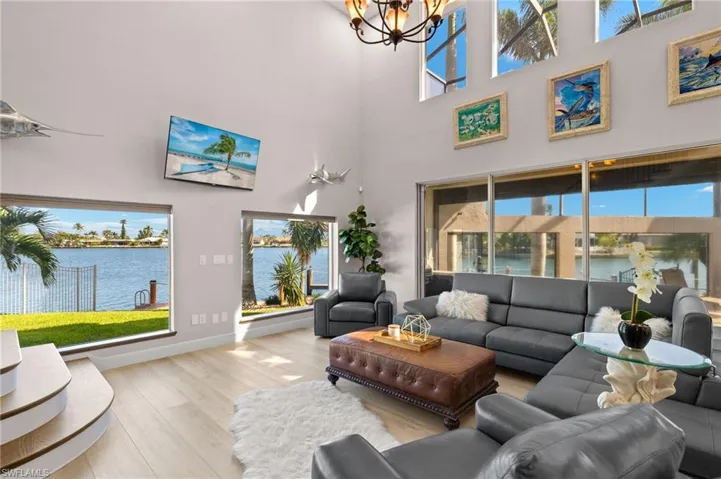 Living area featuring a high ceiling, a notable chandelier, wood finished floors, and a healthy amount of sunlight