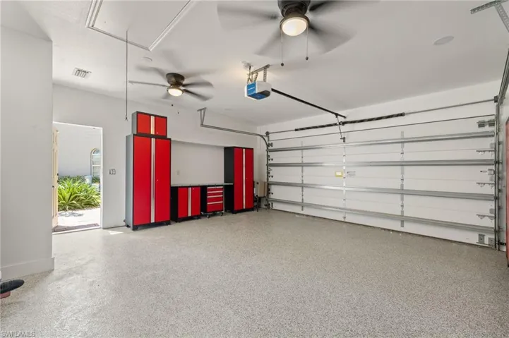 Garage featuring visible vents, a garage door opener, and ceiling fan