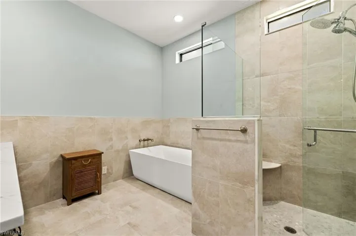 Full Master bathroom with tile walls, a soaking tub, and a stall shower