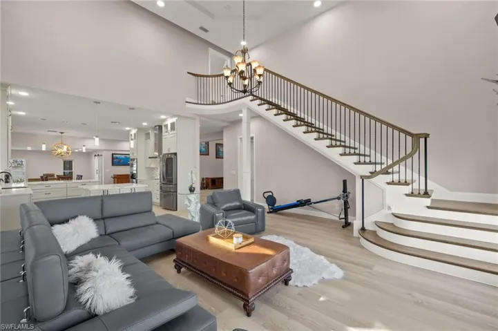 Living area with stairway, a towering ceiling, baseboards, light wood-style flooring, and a notable chandelier