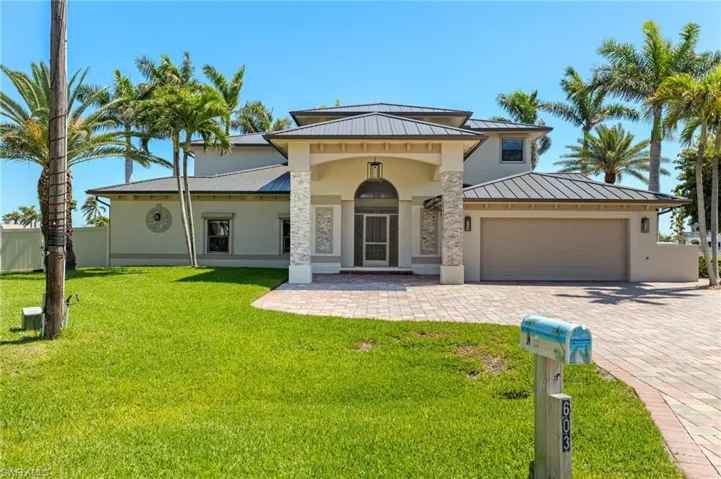 Gorgeous house with decorative driveway, metal roof, a garage, stucco siding, and a standing seam roof