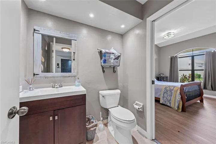 Downstairs guest Bathroom featuring vanity, toilet, and hardwood / wood-style floors