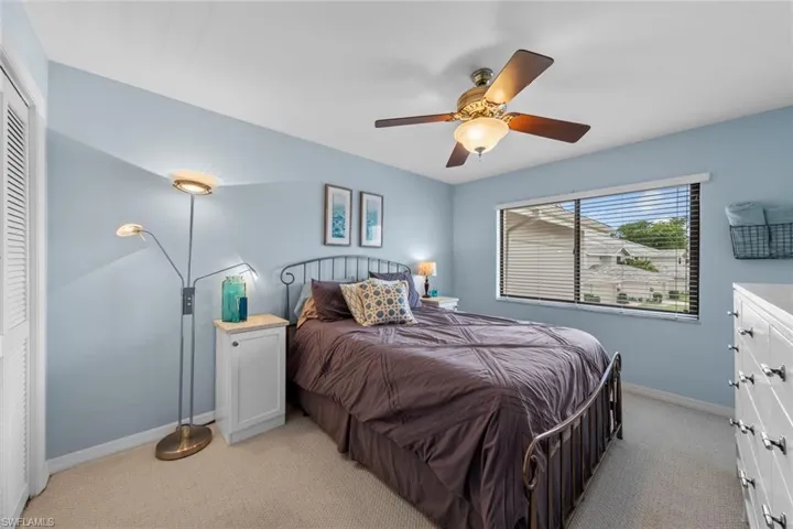 Carpeted bedroom with ceiling fan and a closet
