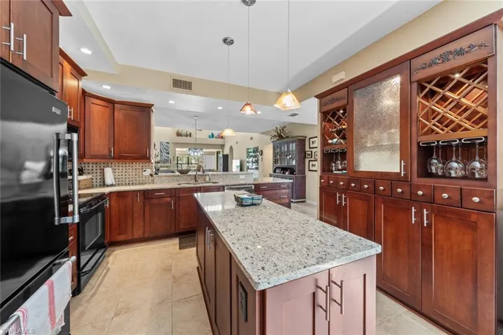Kitchen featuring refrigerator, kitchen peninsula, a center island, hanging light fixtures, and black / electric stove