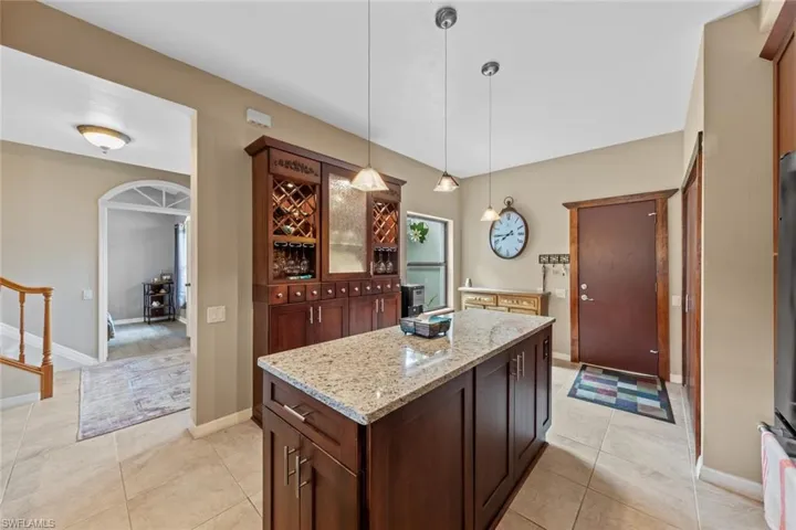 Kitchen with hanging light fixtures, light stone counters, light tile patterned floors, and a kitchen island