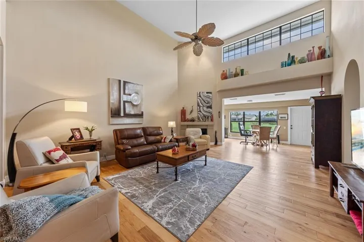 Living room with high vaulted ceiling, ceiling fan, and light wood-type flooring