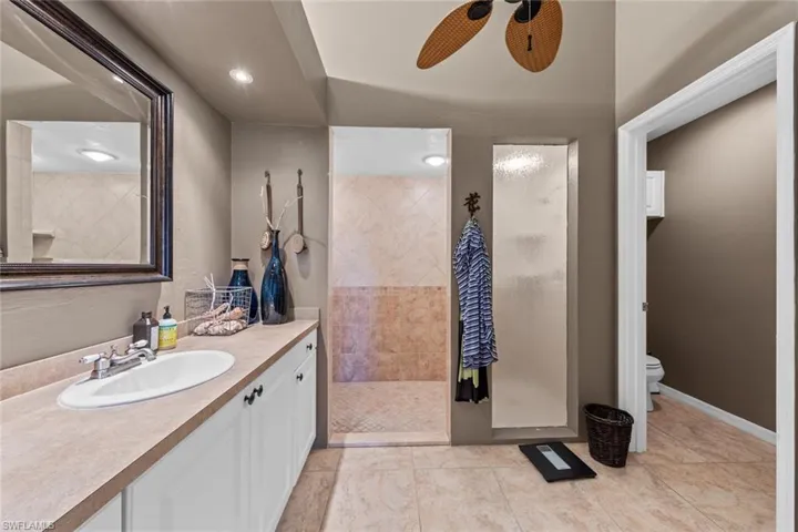 Primary Bathroom with vanity, a tile shower, toilet, tile patterned floors, and ceiling fan