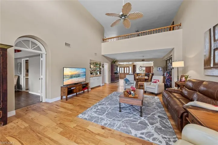 Living room featuring high vaulted ceiling, ceiling fan, and light hardwood / wood-style flooring
