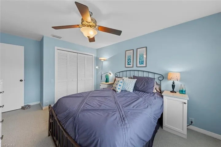 Bedroom with light colored carpet, ceiling fan, and a closet