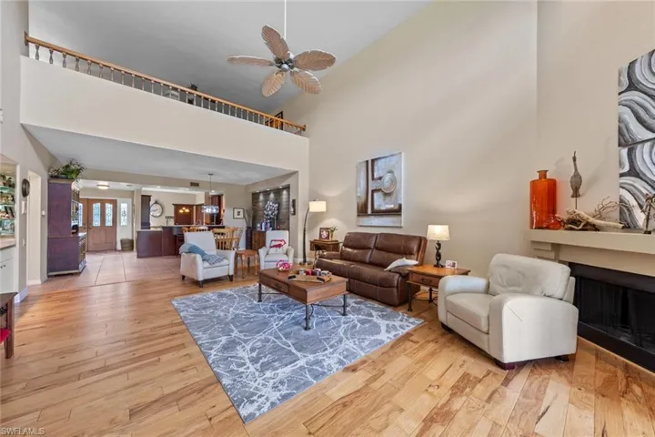 Living room with a towering ceiling, ceiling fan, and light hardwood / wood-style floors