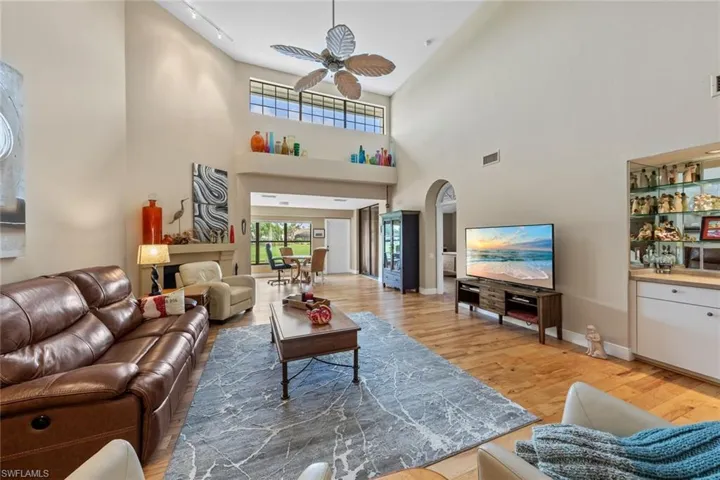 Living room featuring wood-type flooring, a high ceiling, and ceiling fan