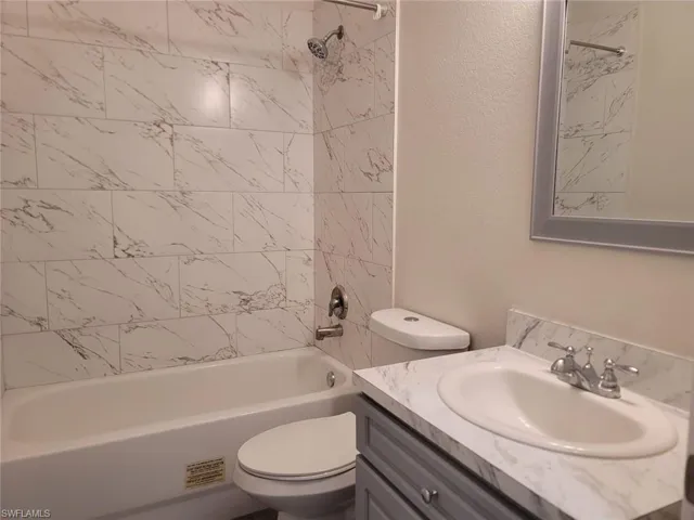 Bathroom featuring bathing tub / shower combination, vanity, and a textured wall