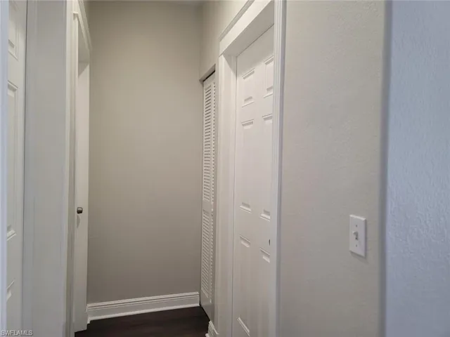Corridor with dark wood-style floors and a textured wall