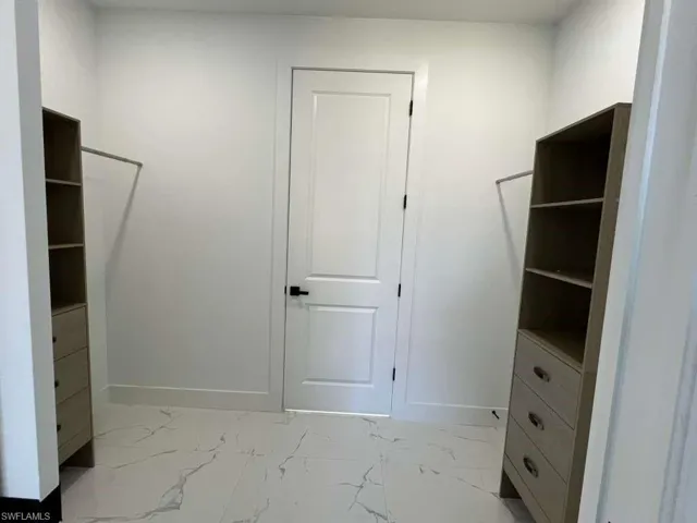 Walk in closet with light marble finish flooring