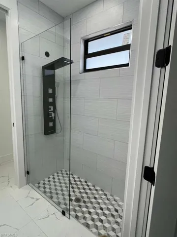 Bathroom with a shower stall and marble finish flooring